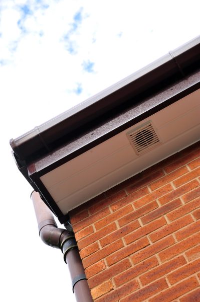 Close-up of white soffits with ventilation and brown fascia and guttering