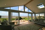 Interior of home extension with Icotherm roof with window/skylight, LED spotlights in ceiling, and sliding doors opening onto a coastal scene